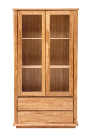 Der Wohnzimmerschrank Celin aus massiver Eiche verbindet die Eleganz einer Vitrine mit der Praktikabilität von Schubladen. Dank seiner klaren Linien, Kurven und der natürlichen Holzmaserung wirkt er zeitlos und macht jede Einrichtung gemütlich.