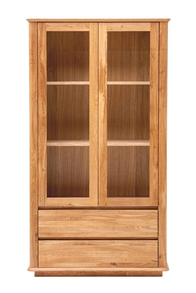 Der Wohnzimmerschrank Celin aus massiver Eiche verbindet die Eleganz einer Vitrine mit der Praktikabilität von Schubladen. Dank seiner klaren Linien, Kurven und der natürlichen Holzmaserung wirkt er zeitlos und macht jede Einrichtung gemütlich.