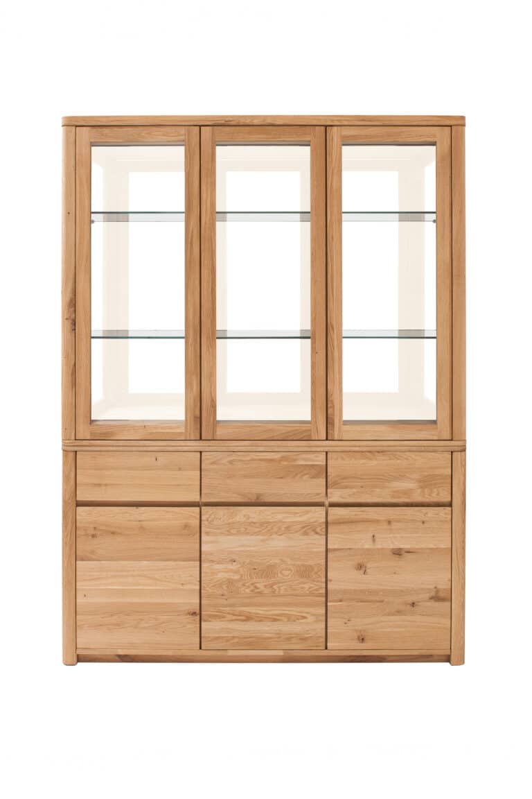 Massive Eichenvitrine Lausanne Wild 3 – zeitlose Eleganz und natürlicher Charakter der Wildeiche. Drei Glastüren bieten Platz für Dekorationen oder Geschirr, während drei praktische Schubladen with Soft-Close-System und großzügiger Stauraum hinter drei Türen die Schönheit von Massivholz mit Alltagstauglichkeit verbinden.