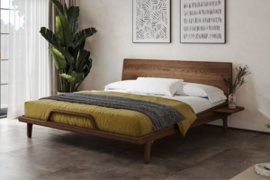 Modernes Bett aus massiver Esche im eleganten Nussbaum-Farbton mit hohem Kopfteil, stilvollem Holzrahmen und einem originellen Design-Detail im Fußbereich. Sanfte Kurven und eine luftige Konstruktion schaffen ein harmonisches Möbelstück mit zeitlosem Design.
